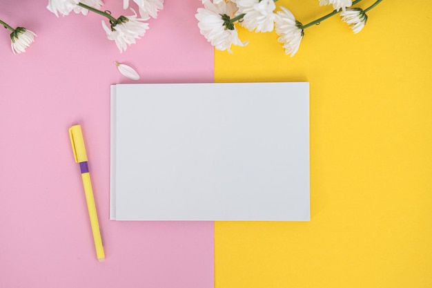 Un cahier et un stylo propres sur une table rose clair Le concept de minimalisme d'affaires pour les femmes