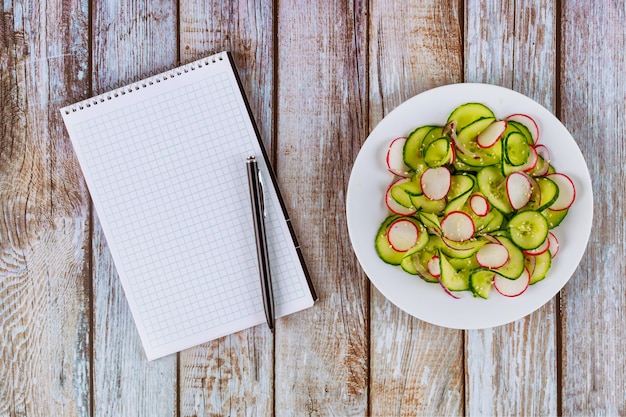 Cahier avec stylo et salade sur table en bois