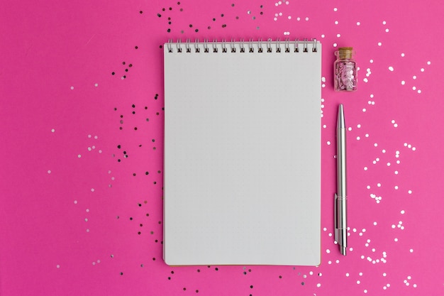 Cahier et stylo sur surface rose