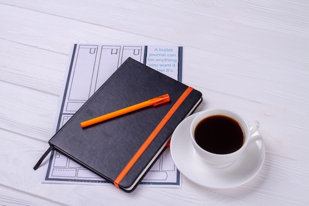 Cahier avec stylo et tasse de café.