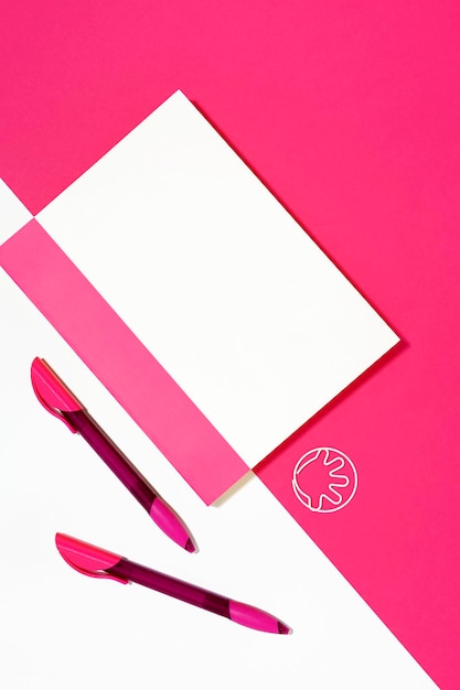 Cahier avec stylos sur fond rose et blanc avec espace de copie