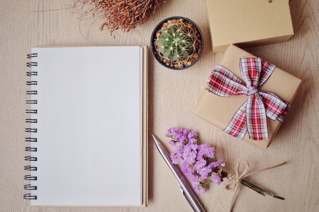 Cahier sur la table en bois et bouquet de fleurs.