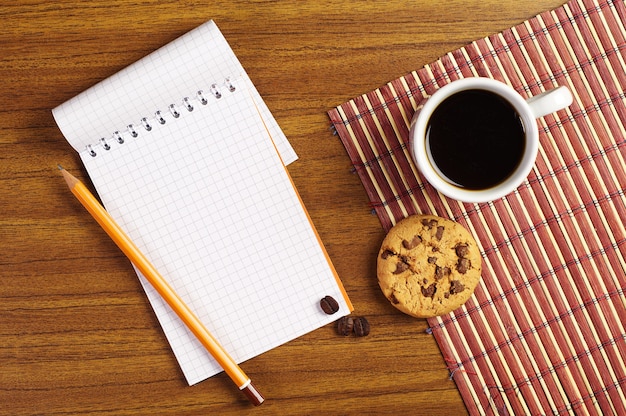 Cahier et tasse de café avec des biscuits au chocolat