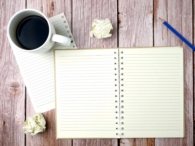 Cahier avec une tasse de café sur fond de texture en bois