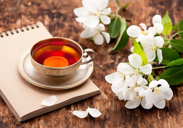 Cahier de tasse de thé et fleurs printanières blanches sur une table en bois