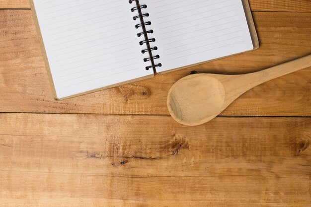 Cahier vide et cuillère sur une table en bois de brun