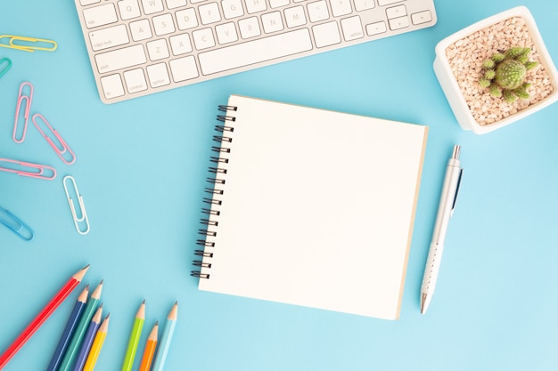 Cahier vierge avec clavier et stylo sur bleu