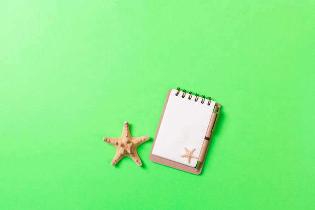 Cahier vierge avec coquillage pour fond vert de vacances d'été, vue de dessus Concept de mise à plat.