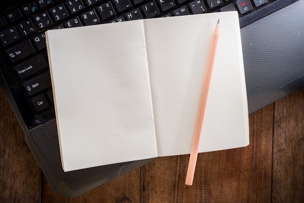 Cahier vierge avec un crayon sur un ordinateur portable