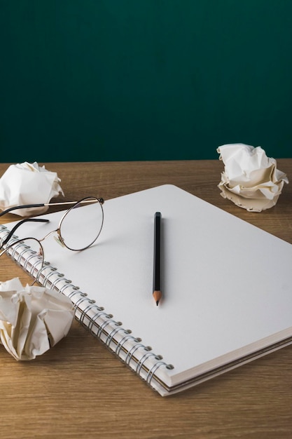 Un cahier vierge avec un crayon sur une table en bois et des boules de papier froissées à partir d'idées de verres