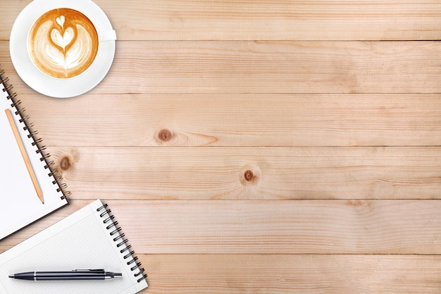 Un cahier vierge ouvert avec un crayon et une tasse de café sur une table en bois Café d'art latte sur le dessus