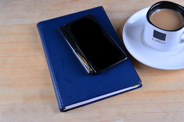 Cahier vierge, stylo plume, smartphone et tasse de café sur le bureau