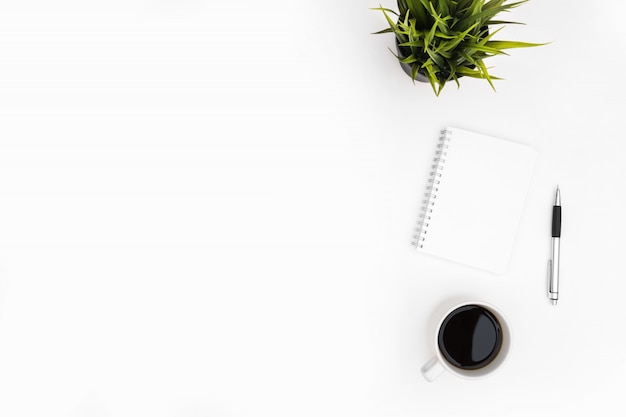 Photo un cahier vierge avec un stylo se trouve sur la table de bureau blanche avec une tasse de café. vue de dessus avec espace de copie, pose à plat.