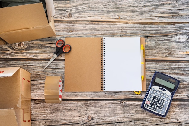 Cahier vierge sur la table à côté des boîtes en carton et de la calculatrice