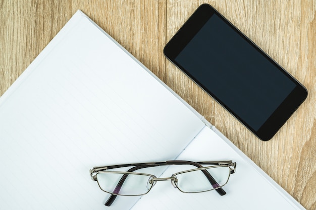 Cahier vierge avec téléphone portable et lunettes