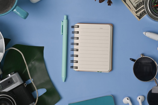 Cahier vue de dessus et accessoires personnels sur fond bleu.