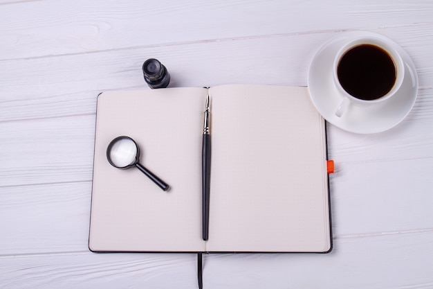 Cahier vue de dessus avec loupe en verre et tasse de café.