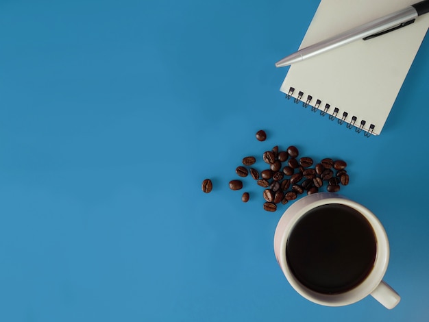 Cahier de vue de dessus, stylo et une tasse de café sur un bureau bleu avec espace copie