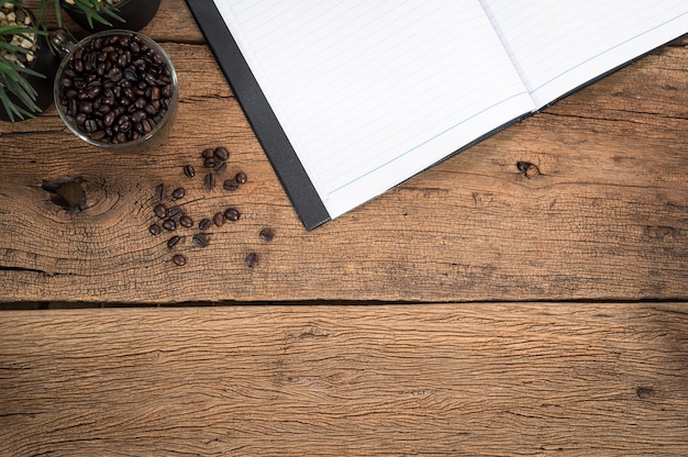 Cahiers et tasse de grains de café placés sur une vue de dessus de table en bois