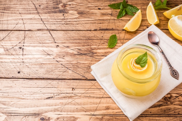 Caillé au citron fait maison dans des bocaux en verre avec citrons frais, fond en bois rustique