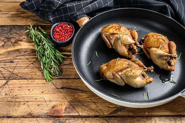 Caille de pigeon rôti maison dans une casserole. Fond en bois. Vue de dessus. Copiez l'espace.