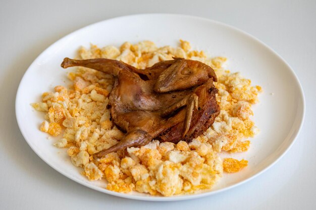 La caille préparée sur une assiette avec des pâtes et des miettes d'œufs