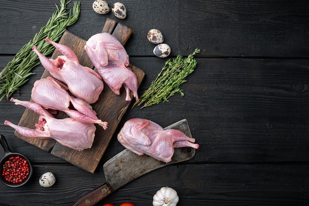 Cailles de viande crue fraîche prête pour la cuisson, mise à plat, sur table en bois noir