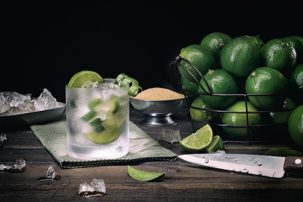 Caipirinha traditionnel brésilien (cachaça, citron et sucre) - fond noir et table en bois