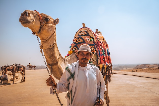 Le Caire, Egypte; Octobre 2020: Portrait d'un vendeur local avec son chameau à la pyramide de Kefren. Les Pyramides de Gizeh, le plus ancien monument funéraire du monde