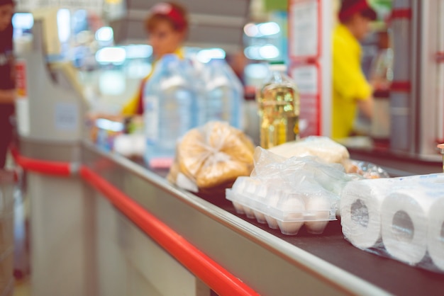 Caissier de supermarché avec de la nourriture sur le convoyeur à acheter le week-end