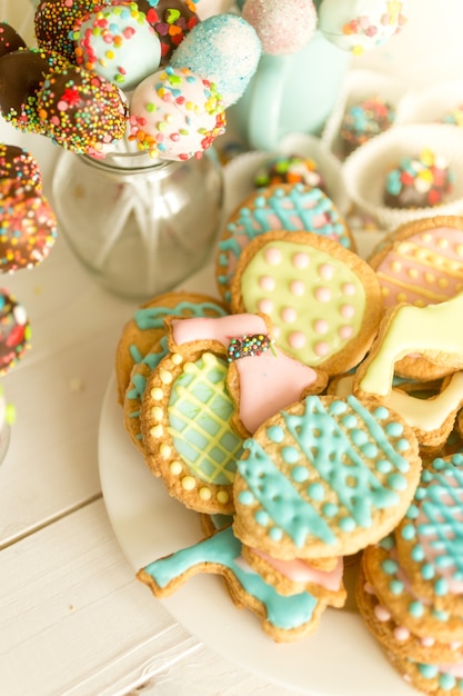 Cake pops et biscuits colorés sur un bureau en bois blanc