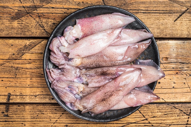 Calamars frais calmars crus dans une assiette Fond en bois Vue de dessus