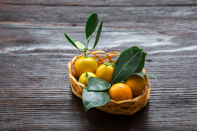 Calamondine aux agrumes avec des feuilles dans le panier sur planche de bois