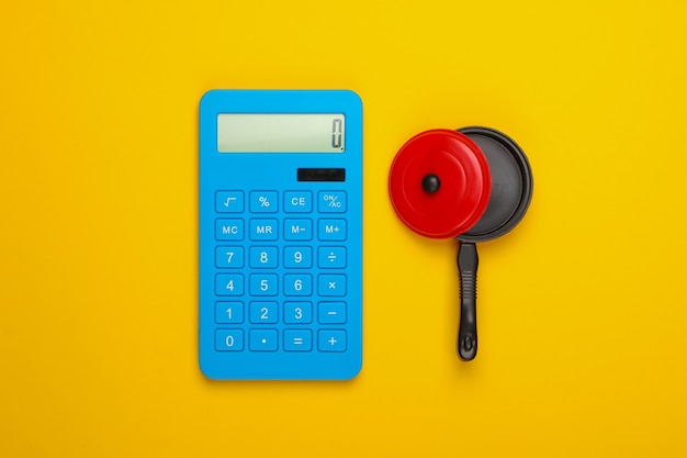 Calcul du coût de la cuisine. Calculatrice et pan de jouet sur fond jaune. Vue de dessus. Minimalisme