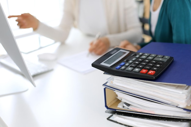 La calculatrice et les classeurs avec papiers attendent d'être traités par une femme d'affaires ou un comptable travaillant au bureau dans le bureau de retour dans le flou Audit interne et concept fiscal