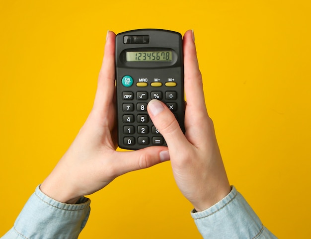 Calculatrice de comptage de mains féminines sur un jaune.