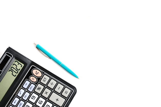 Calculatrice éteinte et un stylo à bille sur fond blanc