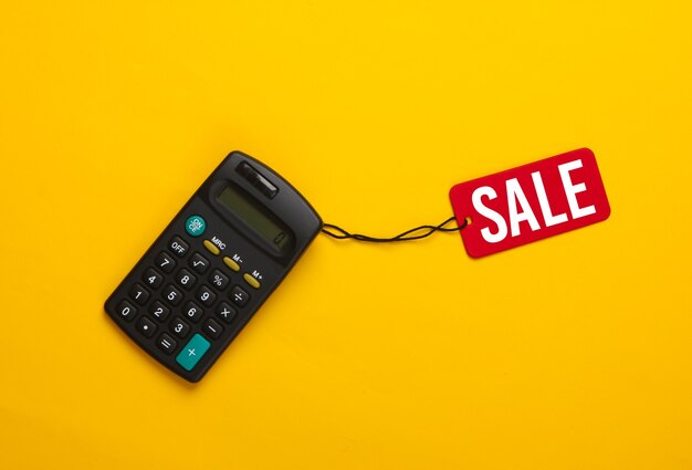 Calculatrice avec une étiquette de vente rouge sur jaune. Grande vente, réductions.