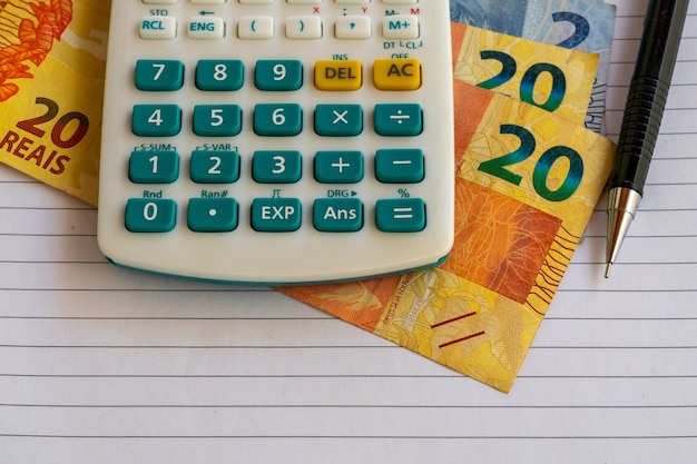 Calculatrice, factures d'argent brésilien sur une feuille de papier avec un crayon mécanique