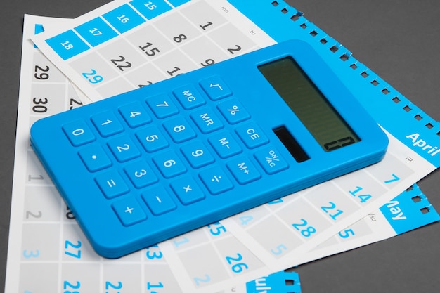 Calculatrice avec les feuilles du calendrier mensuel sur gris. Calcul des loyers pour le logement.