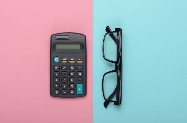 Calculatrice et lunettes classiques sur un bleu rose