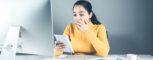 Calculatrice de main de femme triste au bureau