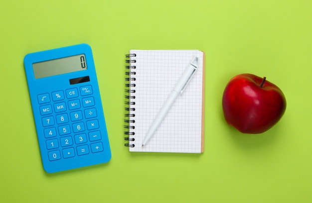 Calculatrice avec ordinateur portable, pomme sur vert. Retour à l'école. Concept d'éducation