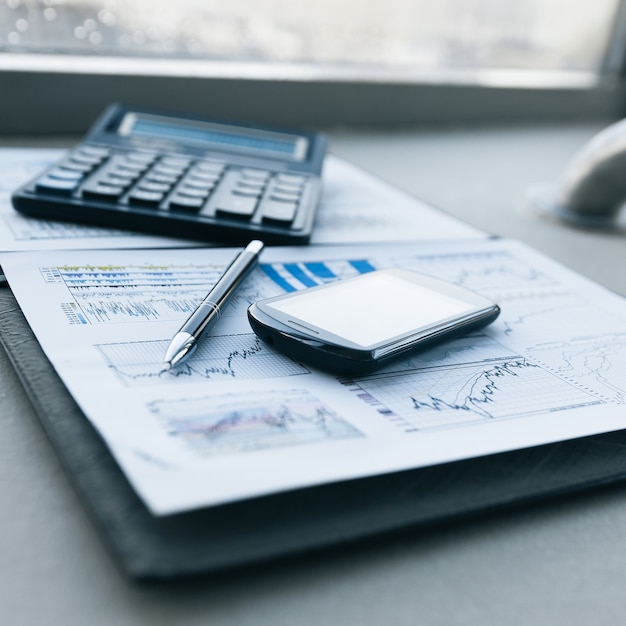 Calculatrice, smartphone et documents financiers sur le businessm