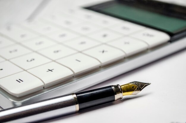 Calculatrice et un stylo sur le fond blanc