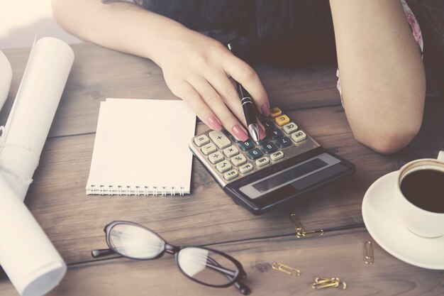 Calculatrice et stylo de main de femme sur la table de travail