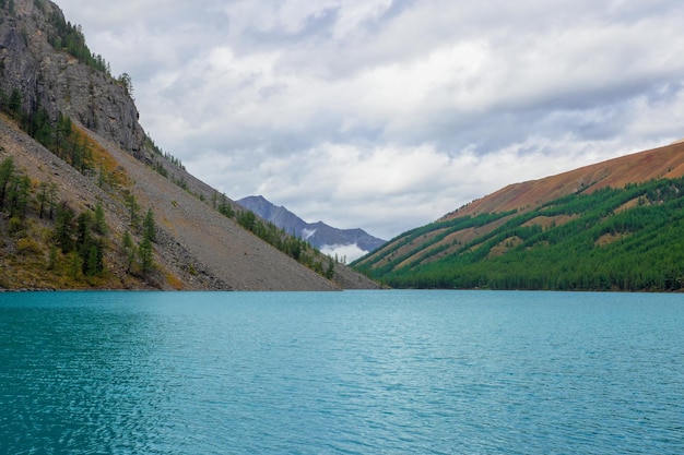 Caldera remplie d'eau turquoise, un ancien lac relique sur fond de montagnes boisées.