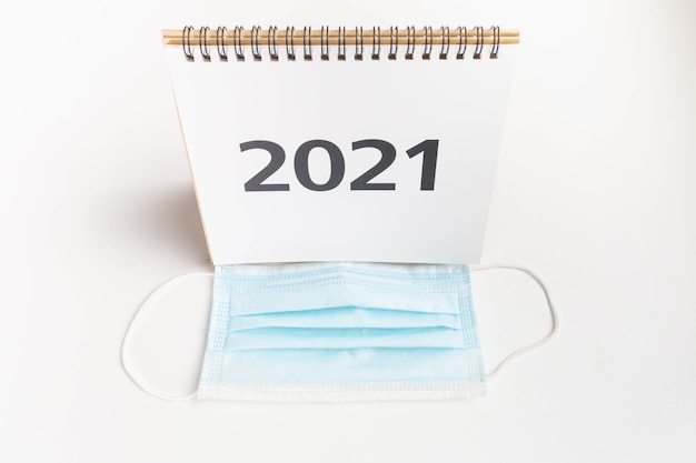 calendrier 2021 devant un masque facial sur fond blanc