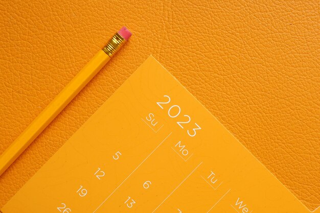 Calendrier de l'année 2023 de couleur orange et un crayon sur la table