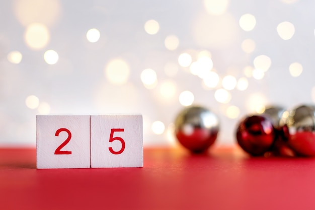 Calendrier de l'Avent en bois le 25 décembre sur fond blanc et rouge avec des boules de Noël. Copiez l'espace pour le texte